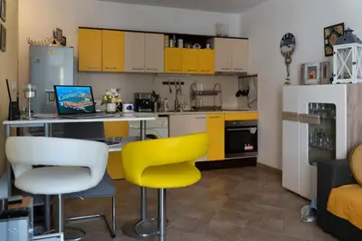 a kitchen with yellow cabinets and a table and yellow chairs at Sea Time Sozopol in Sozopol