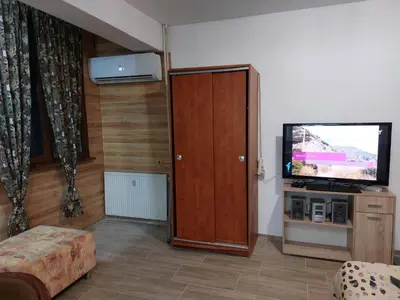 a living room with a television and a wooden cabinet at Студио Тони in Burgas City