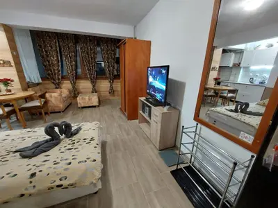 a living room with a television and a room with a bed at Студио Тони in Burgas City