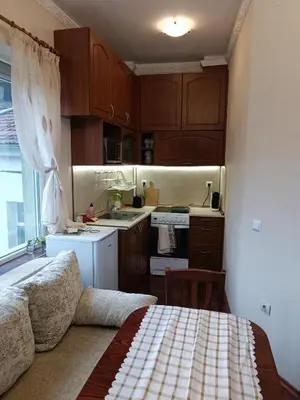 a kitchen with wooden cabinets and a bed in a room at Cozy flat Sisilia center in Varna City