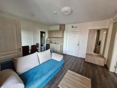 a living room with a blue couch and a kitchen at APART SUN Travel SUNNY BEACH in Sunny Beach