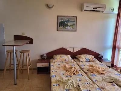 a bedroom with a bed and a table and stool at Complex ELIT Cacao Beach - Apartments for rent- ЕЛИТ Слънчев бряг in Sunny Beach