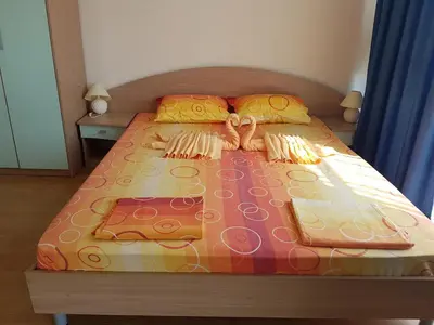 a large bed with a colorful comforter and pillows at Complex ELIT Cacao Beach - Apartments for rent- ЕЛИТ Слънчев бряг in Sunny Beach