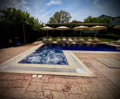 a swimming pool with chairs and umbrellas on a patio at Guest House PETRA- Medovo, Sunny beach in Razvalini Balchikioy