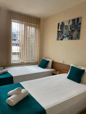 a hotel room with two beds and a window at Хотел ЮГ in Primorsko