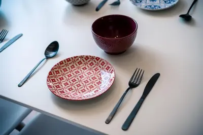 a table with a plate and a bowl and utensils at Sky Residence Burgas with FREE Garage - Sky Apartments Burgas in Burgas City