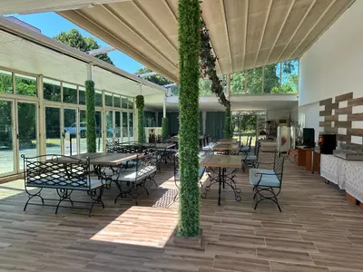 a covered patio with tables and chairs and windows at Hotel Surf Primorsko in Primorsko