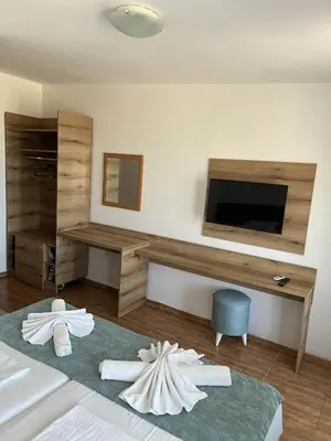 a bedroom with a tv and a bed with towels at Hotel Surf Primorsko in Primorsko