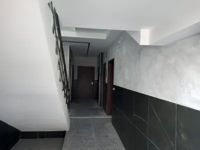 a hallway with a white wall and black tiles at Сарафово Лукс Тераса Първа Линия in Sarafovo