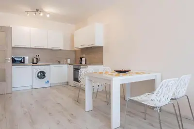 a kitchen with a white table and white chairs at Seaside Apartment in Varna City