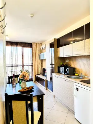 a kitchen with a table with a vase of flowers on it at Студио Каскадас К34 in Sunny Beach