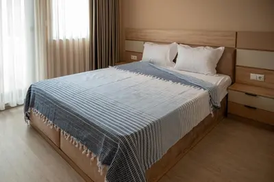 a bedroom with a bed with a blue and white comforter at Ваканционна Къща в Greenn Life Созопол in Sozopol