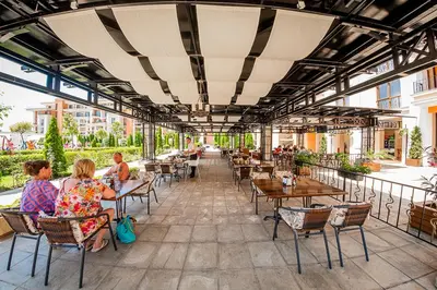 a group of people sitting at tables on a patio at Apartament Prestige Fort - Bastet BS in Sveti Vlas