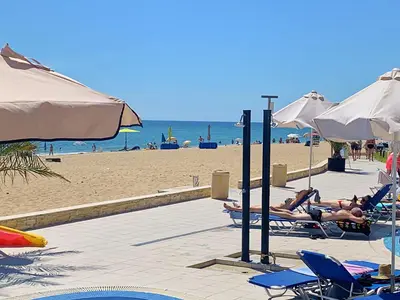 a group of people laying in lawn chairs on the beach at Apartments Obzor Beach B - Апартаменти Обзор Бийч B in Obzor