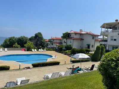 a person laying in lawn chairs near a swimming pool at Caprice Apartment in Lozenec in Kiten