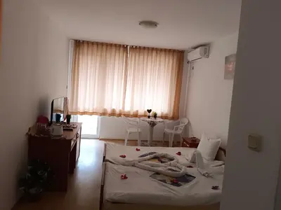 a room with two beds and a table in it at Стаи за гости Ники in Nesebar
