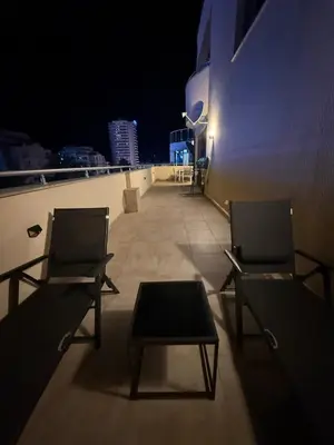 two chairs and a table on a balcony at night at YS Residence in Sunny Beach