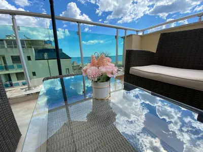 a glass table with a vase of flowers on a balcony at YS Residence in Sunny Beach