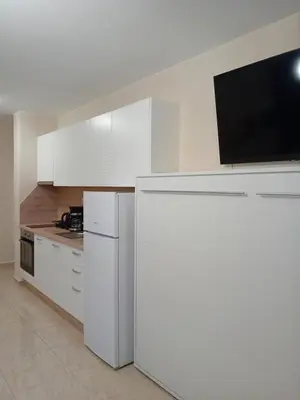 a kitchen with white cabinets and a flat screen tv at Sveti Vlas Sea Dreams apartament in Sveti Vlas