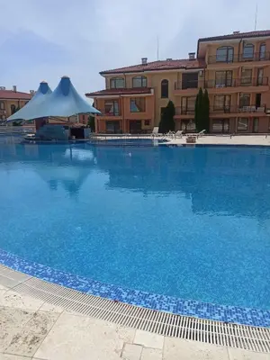 a large blue swimming pool in front of a building at Panorama Dreams - Sveti Vlas - Furnished Apartment with a Terrace and a Sea View in Sveti Vlas