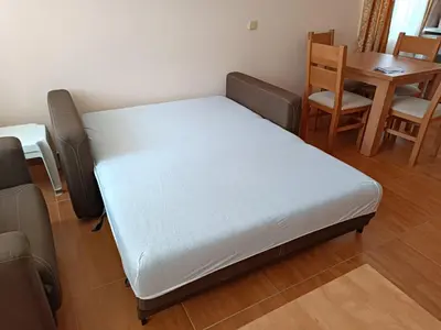 a bed in a room with a table and chairs at Panorama Dreams - Sveti Vlas - Furnished Apartment with a Terrace and a Sea View in Sveti Vlas