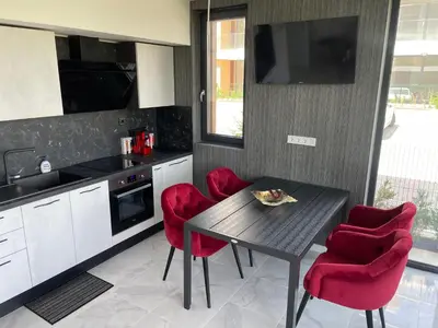 a kitchen with a black table and red chairs at Сарафово Лукс Гарден Първа Линия in Burgas City