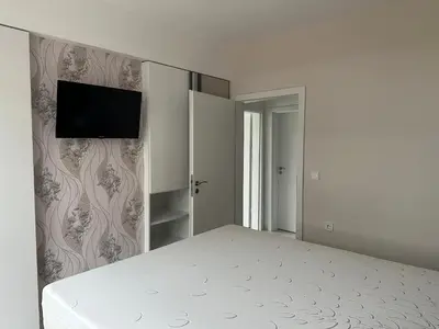 a bedroom with a bed and a tv on a wall at Сарафово Лукс Гарден Първа Линия in Burgas City