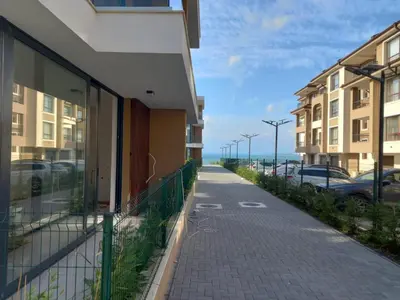a sidewalk next to a building with parked cars at Сарафово Лукс Гарден Първа Линия in Burgas City