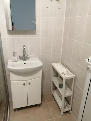 a white bathroom with a sink and a mirror at Римски Терми Варна in Varna City