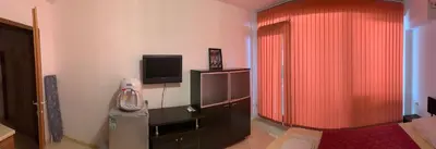 a room with a red curtain and a television at Stamopolu Parter in Primorsko