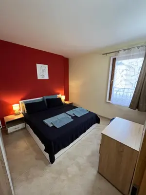 a bedroom with a bed and a red wall at River park 2 bedroom apartment in Nesebar