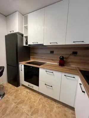 a kitchen with white cabinets and a black refrigerator at River park 2 bedroom apartment in Nesebar