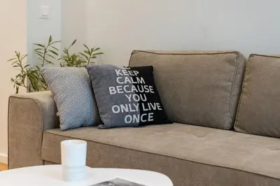 a couch with a pillow that says keep calm because you only live once at Modern & Stylish Sea Apartment with Parking in Burgas City