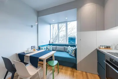 a kitchen with a blue couch and a table and chairs at Modern & Stylish Sea Apartment with Parking in Burgas City