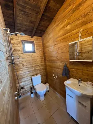 a wooden bathroom with a toilet and a sink at Лятна каравана “Айтата” in Kiten