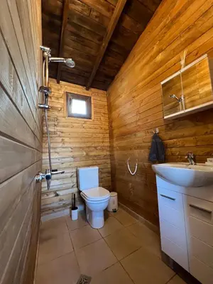 a wooden bathroom with a toilet and a sink at Лятна каравана “Айтата” in Kiten