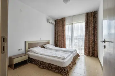 a bedroom with a bed and a large window at Апартамент на плаж Градина in Chernomorets