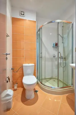 a bathroom with a toilet and a glass shower at Апартамент на плаж Градина in Chernomorets