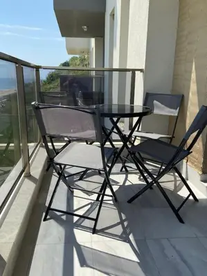 a glass table and two chairs on a balcony at Marino Liberta South Beach Obzor in Obzor