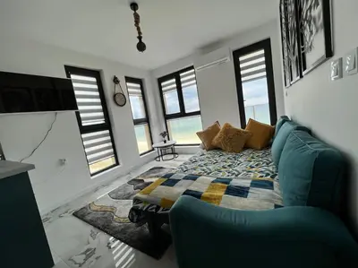 a bedroom with a bed and a couch and windows at Marino Liberta South Beach Obzor in Obzor