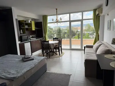 a living room with a bed and a kitchen with a table at Top Studio in Big Kamelia Holiday Complex Sunny Beach in Sunny Beach