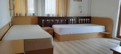 a room with two beds and a table and a desk at Anchors Guest House in Sozopol
