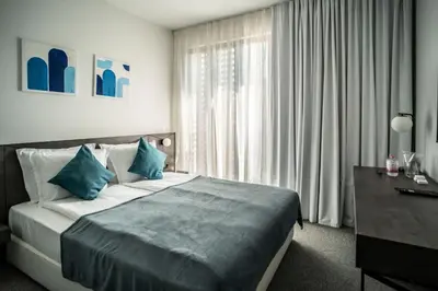 a bedroom with a bed with blue pillows and a desk at Bizarre Boutique Hotel in Varna City