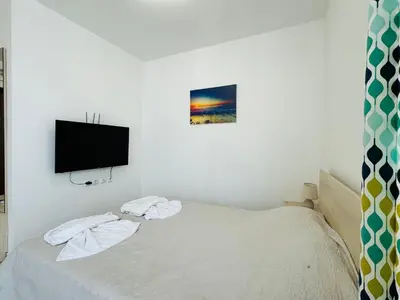 a bedroom with a bed with a tv on the wall at HORIZON 38 'Б' Studio Sveti Vlas in Sveti Vlas