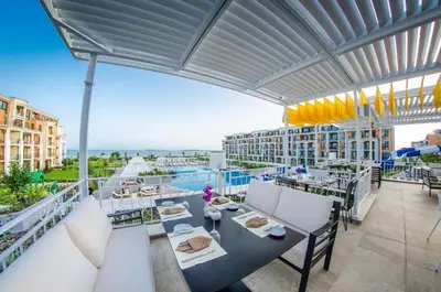 a balcony with tables and chairs on a building at Seaside Serenity Studio - Premier Fort Beach in Sveti Vlas