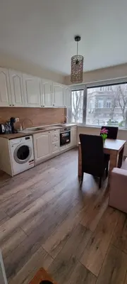 a kitchen with white cabinets and a wooden floor at Central Luxe Apartament Mimoza in Varna City