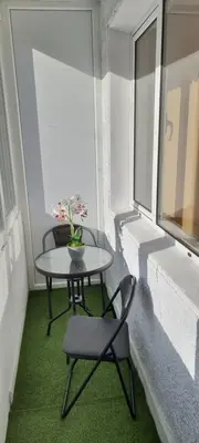 a small table and chair in a room with a window at Central Luxe Apartament Mimoza in Varna City