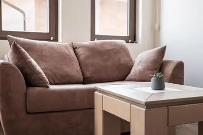 a brown couch with pillows sitting next to a table at Studio in Garden of Eden D402 - Sveti Vlas, Bułgaria in Sveti Vlas