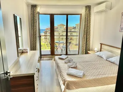 a bedroom with a bed and a large window at Sunshine apartment in Shkorpilovtsi