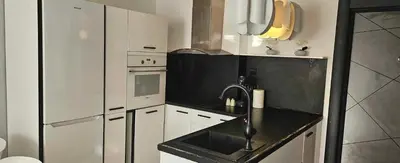 a kitchen with white cabinets and a black counter top at Апартамент ЛазуР in Burgas City